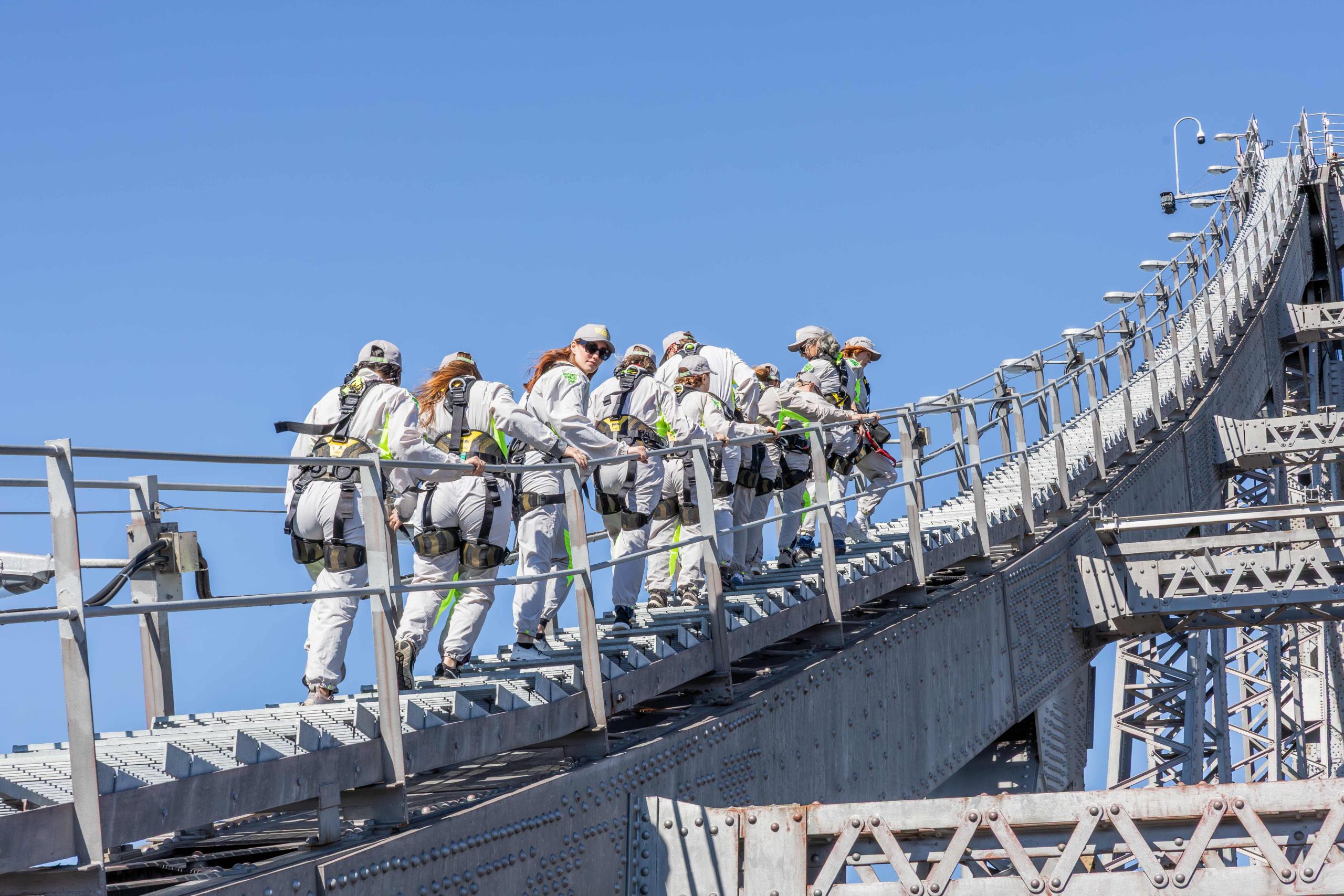Climbers in safety harnesses on the Story Bridge Adventure Climb with Brisbane River views below